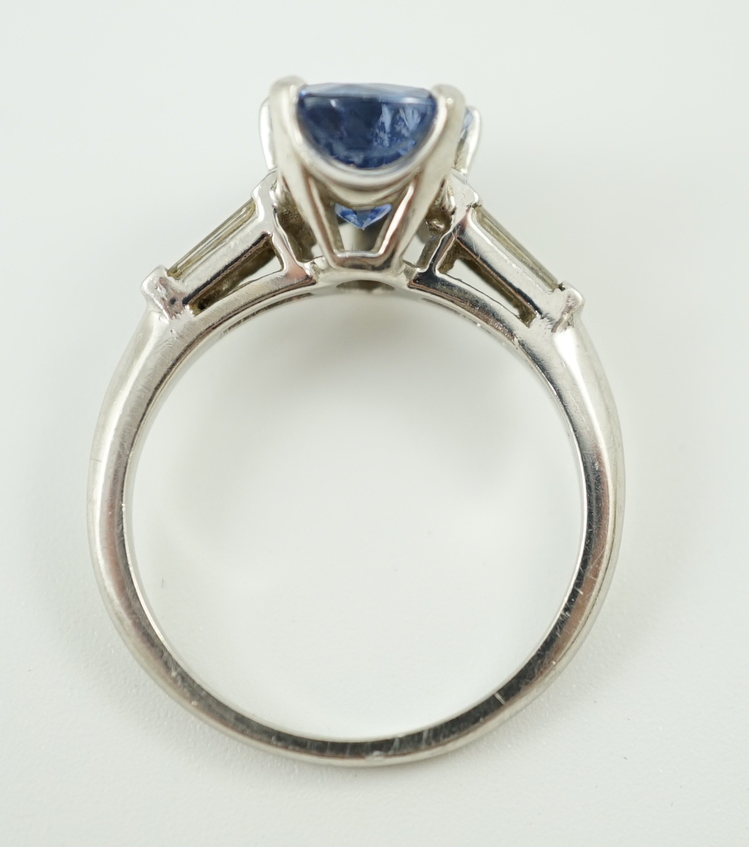 A platinum (10%) and single stone pear cut Ceylon sapphire set ring, with tapered baguette cut diamond set shoulders